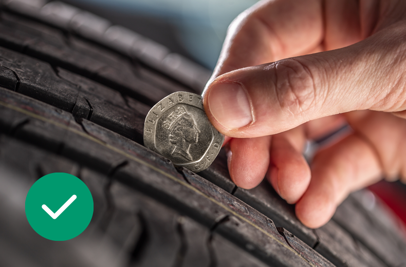 A person using a tread depth gauge to check a car tyre during a pre-purchase inspection.