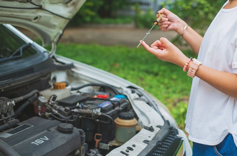 Checking the engine oil level and condition on a dipstick, looking for clean, light-brown oil.