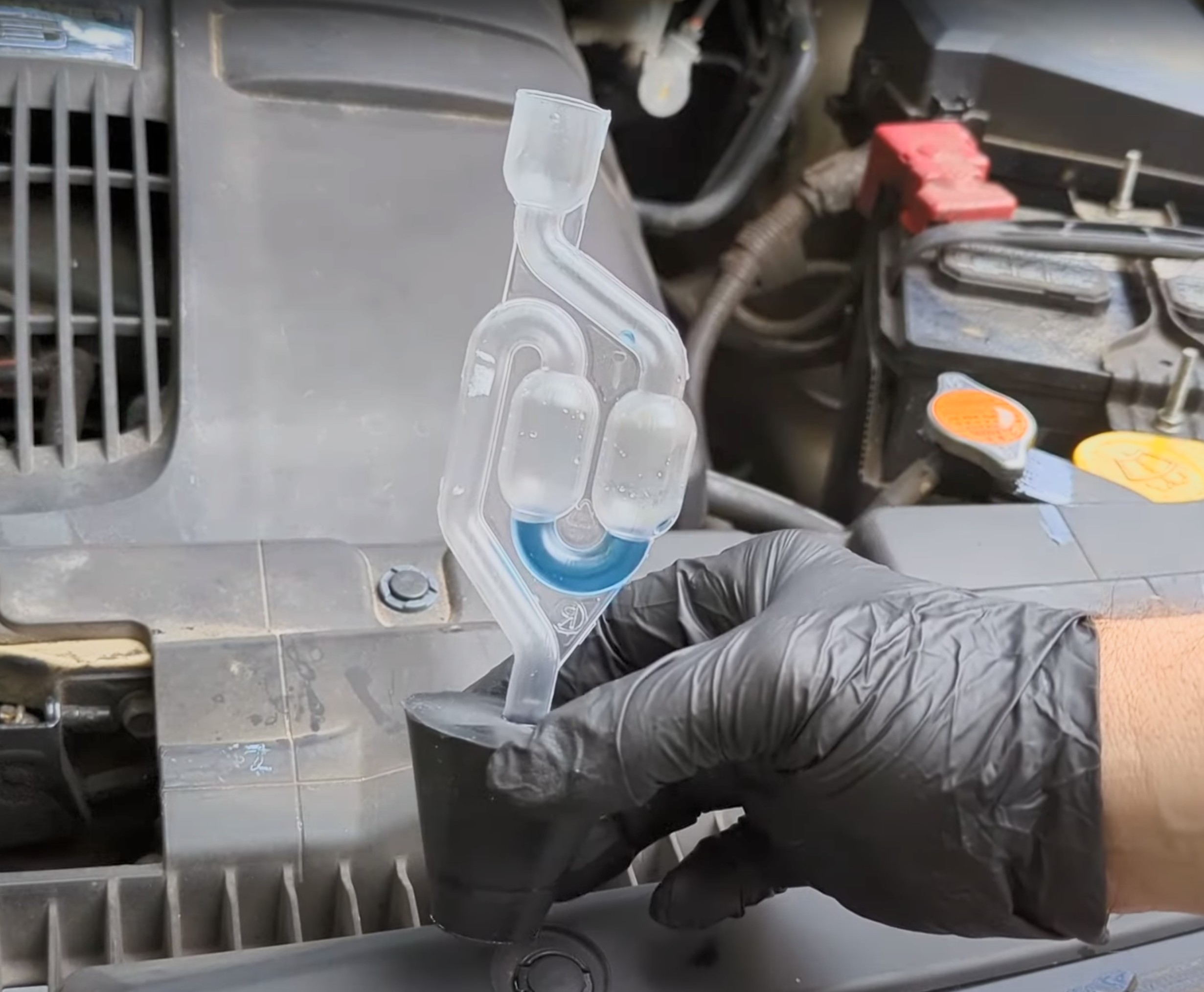 A DIY mechanic using a combustion leak tester on a car engine.